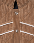 Luxury Western Golf apparel Close-up of a brown quilted jacket with white trim and buttons.