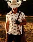 Luxury Western Golf apparel man wearing golf polo with agave print and a cowboy hat while holding a leather golf bag.