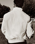 Luxury Western Golf apparel Person wearing a white jacket standing outdoors with trees and a fence in the background