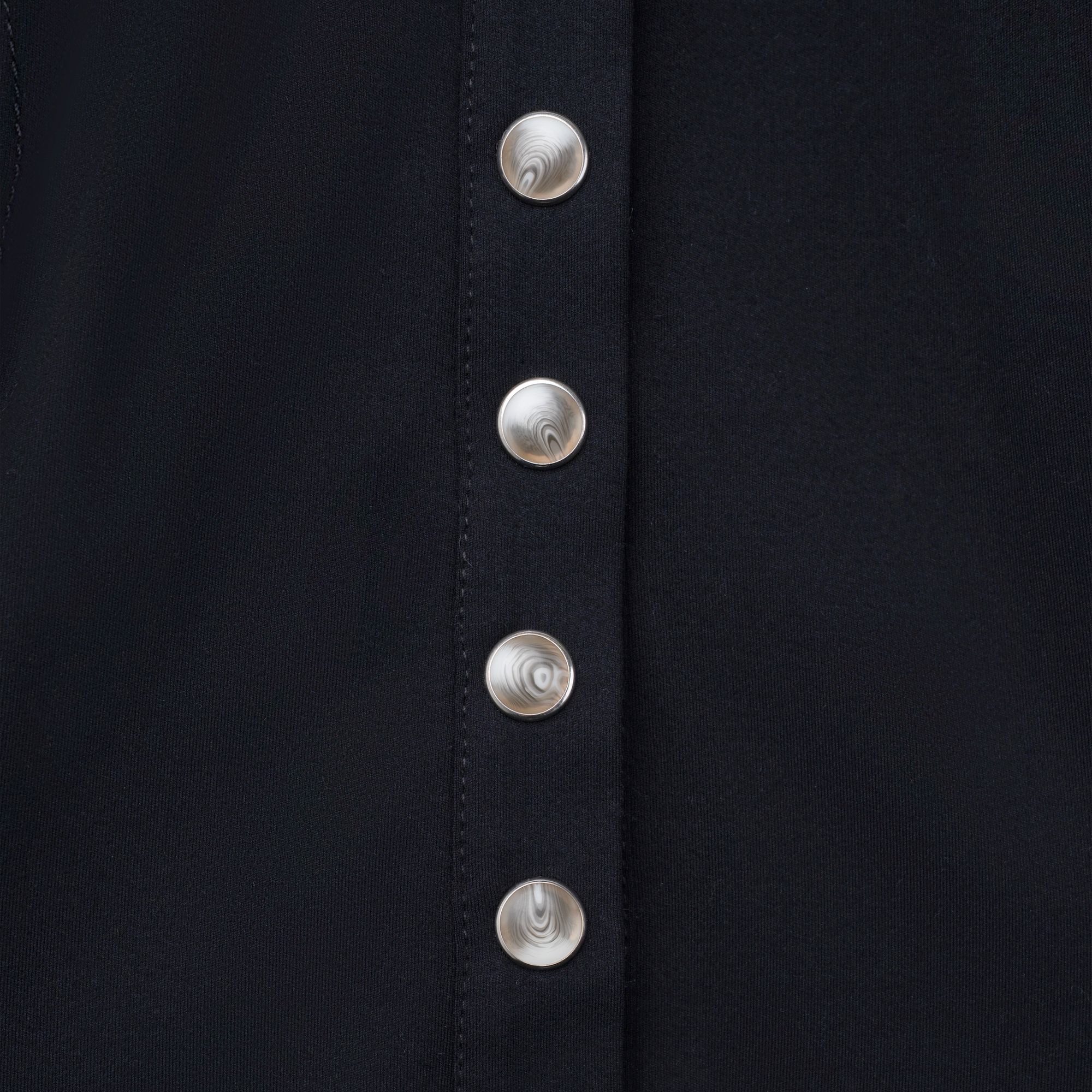 Luxury Western Golf apparel Close-up of a black garment with silver buttons on a dark background