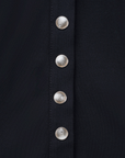 Luxury Western Golf apparel Close-up of a black garment with silver buttons on a dark background
