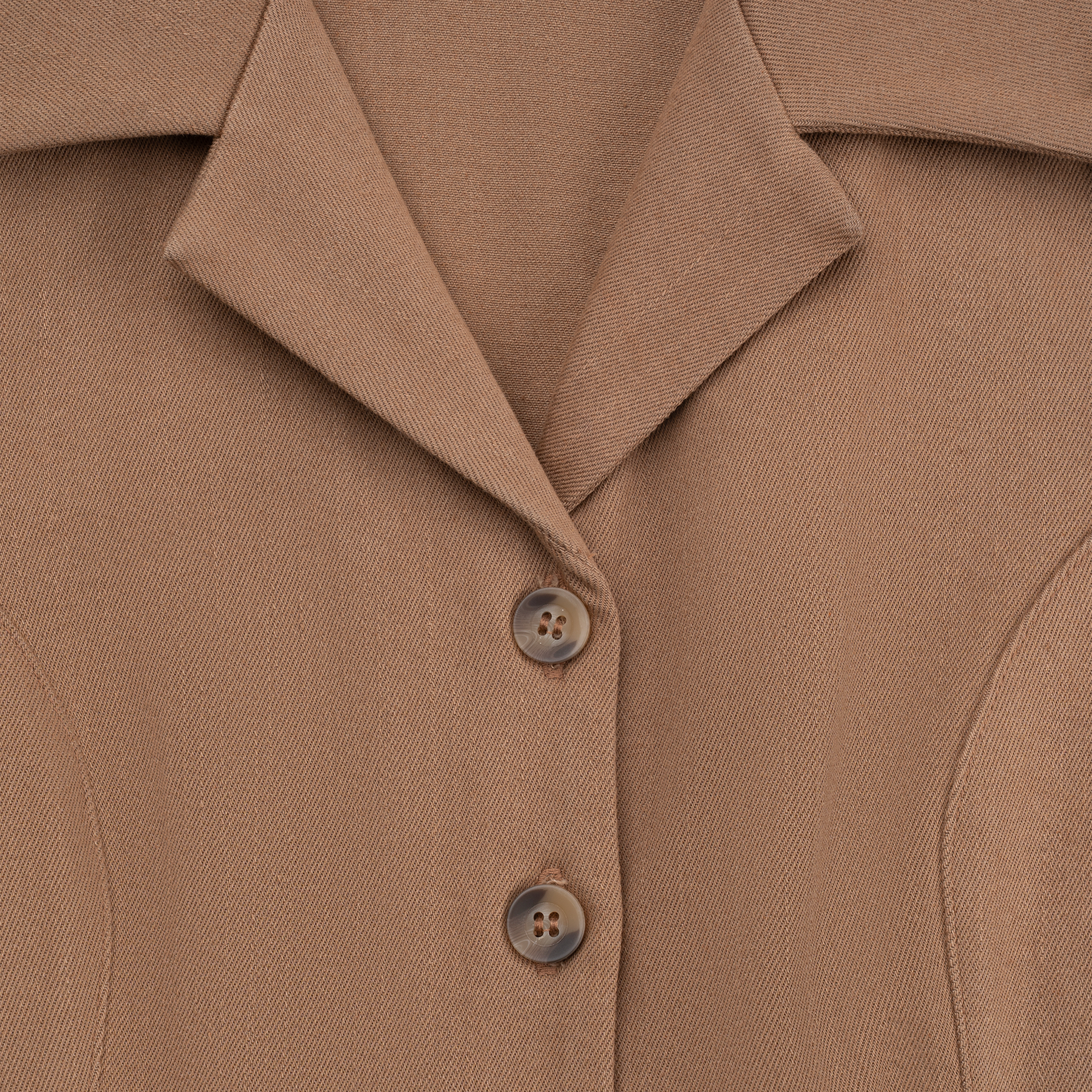 Close-up of a brown jacket with buttons on a matching fabric background