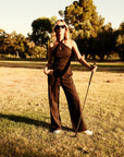 Luxury Western Golf apparel Woman in a black two piece jumpsuit standing in a grassy field with trees in the background
