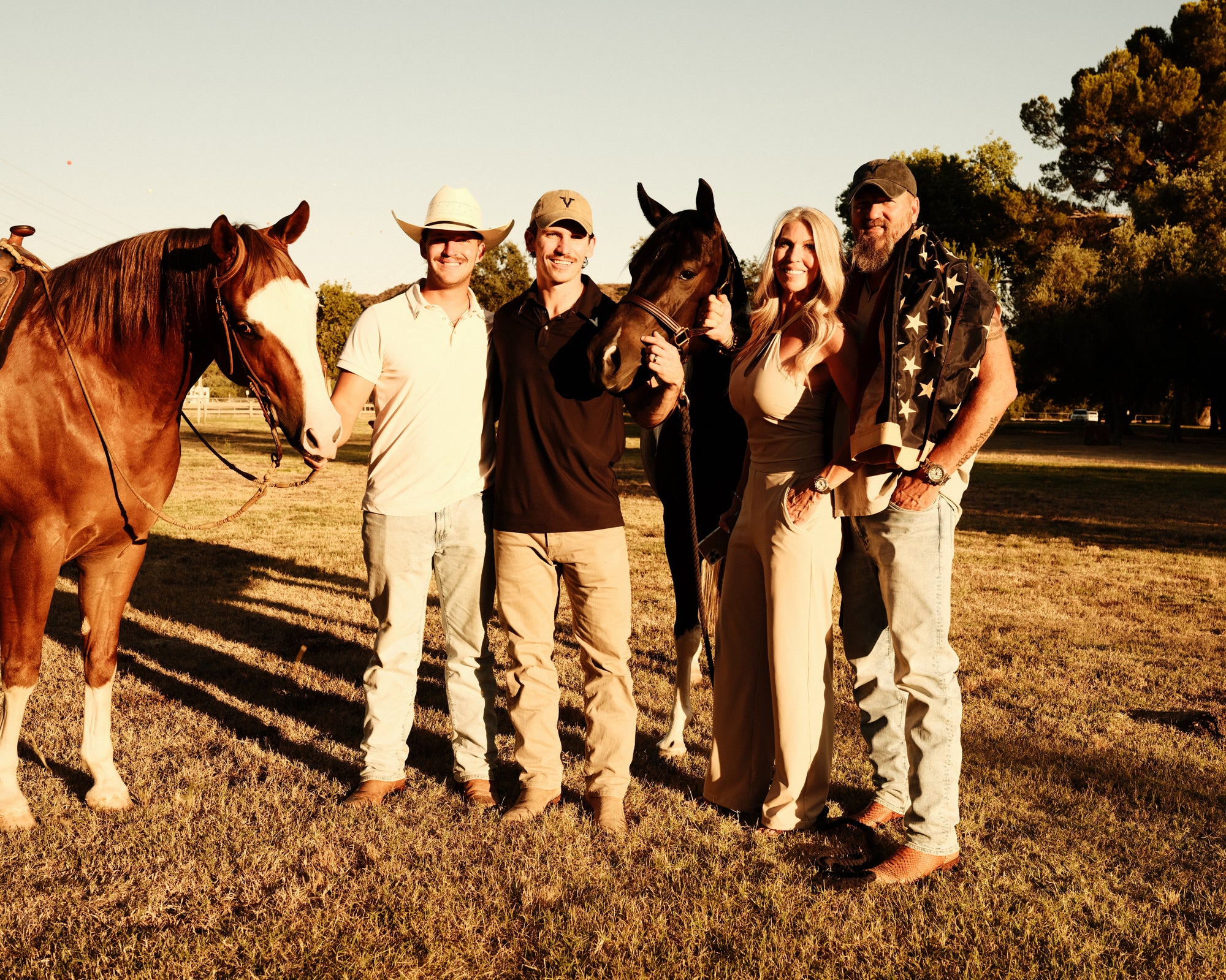 3 men and a women standing with 2 horses while all are wearing Maverix apparel