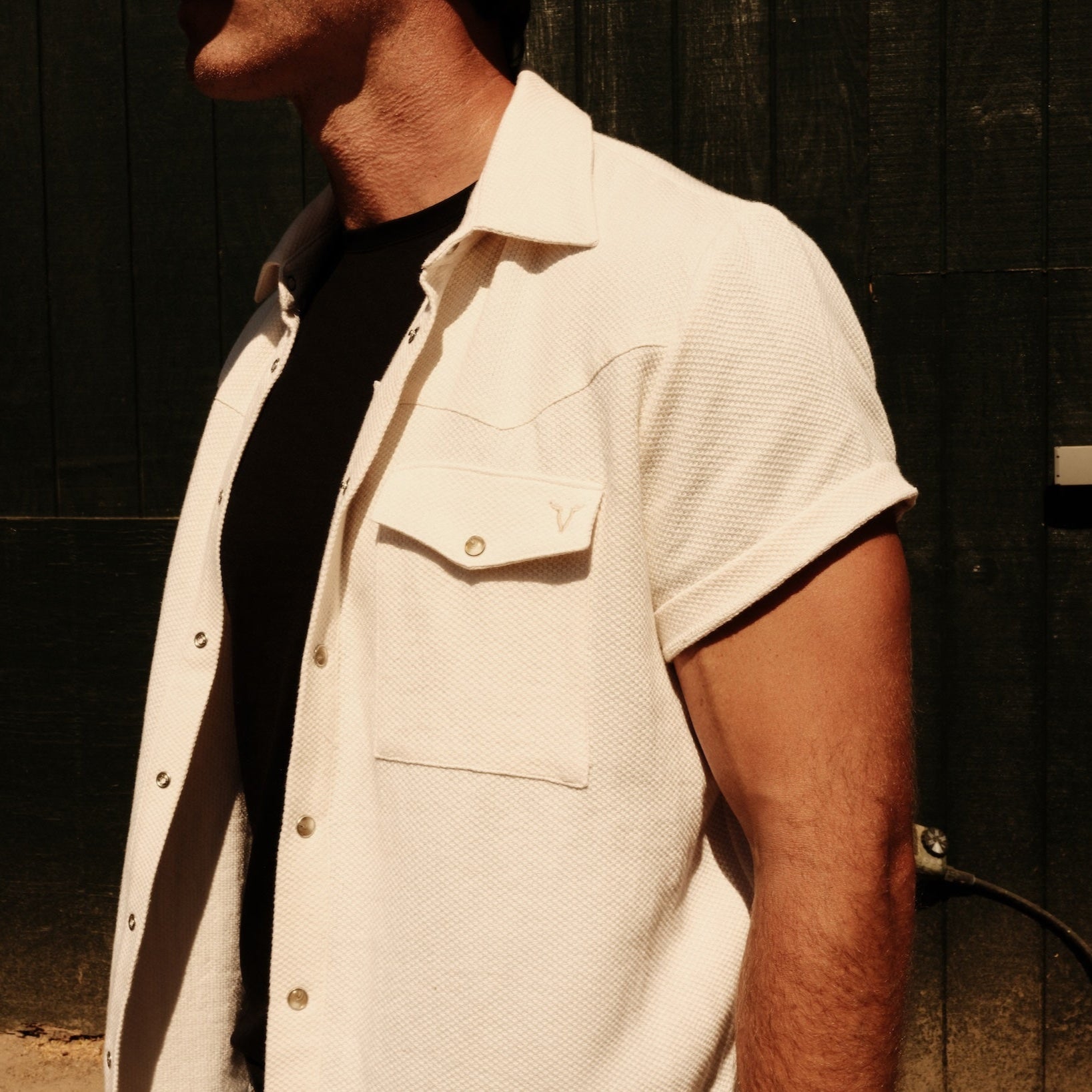 Luxury Western Golf apparel Person wearing a white short-sleeve shirt over a black shirt against a dark background