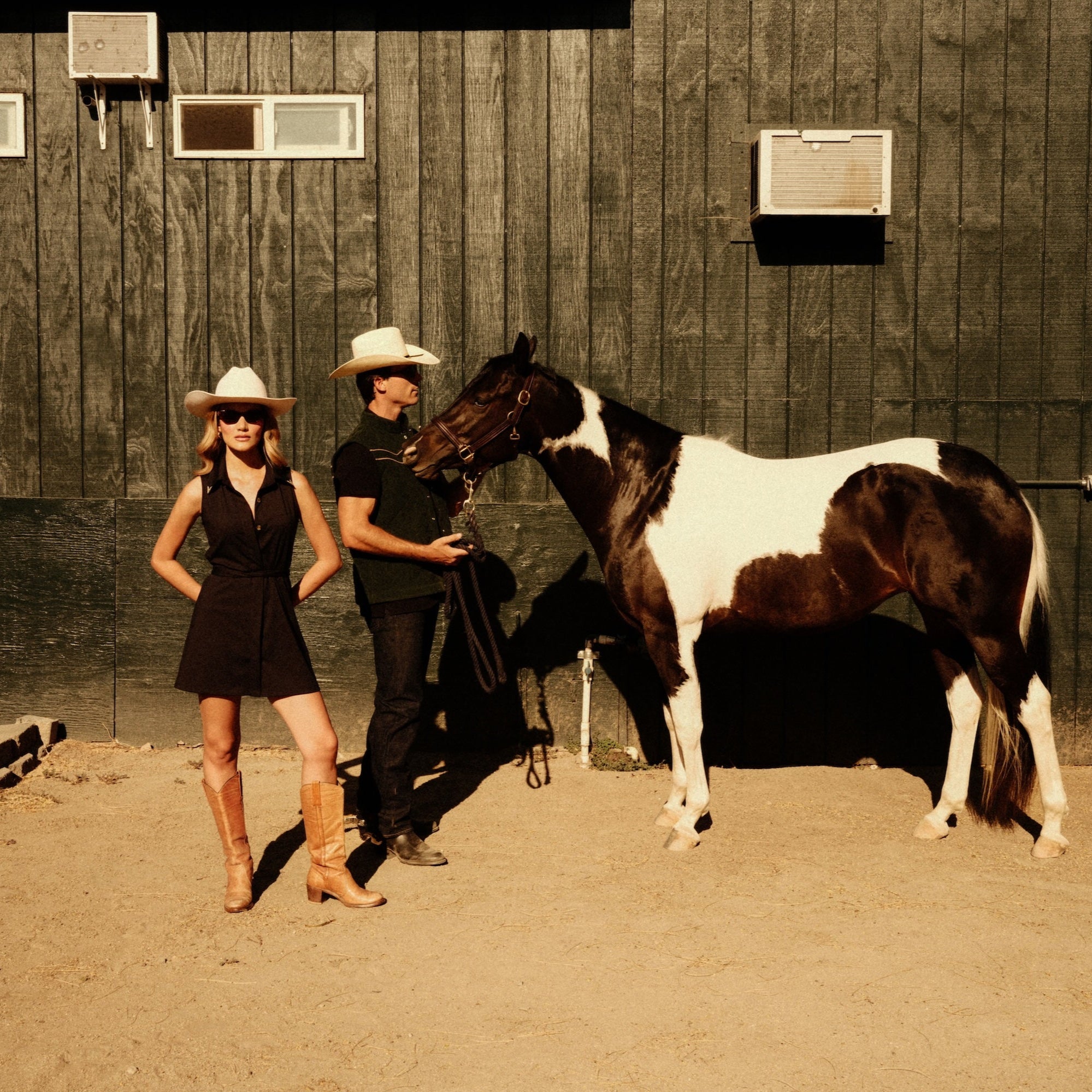 Luxury Western Golf apparel Two people in cowboy hats standing next to a horse in front of a wooden building.