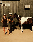 Luxury Western Golf apparel Two people in cowboy hats standing next to a horse in front of a wooden building.