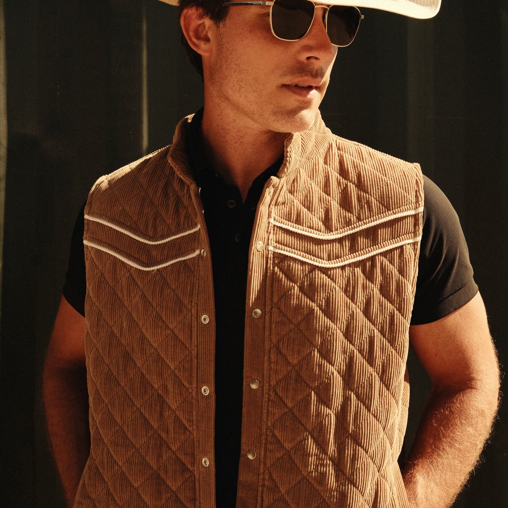 Luxury Western Golf apparel Man wearing a quilted vest, white cowboy hat, and sunglasses against a dark background